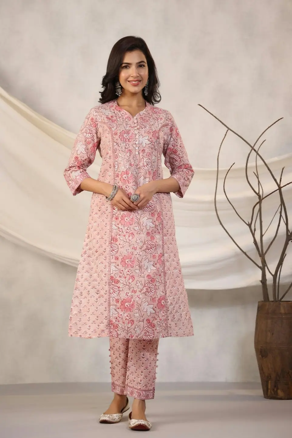 Woman poses in a pink floral kurta and pants.